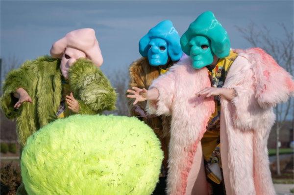 People wearing furry coats of pink, gold and green and wearing masks of green, 蓝色和粉红色的人站在绿色的人面前，用手做手势, furry sphere.